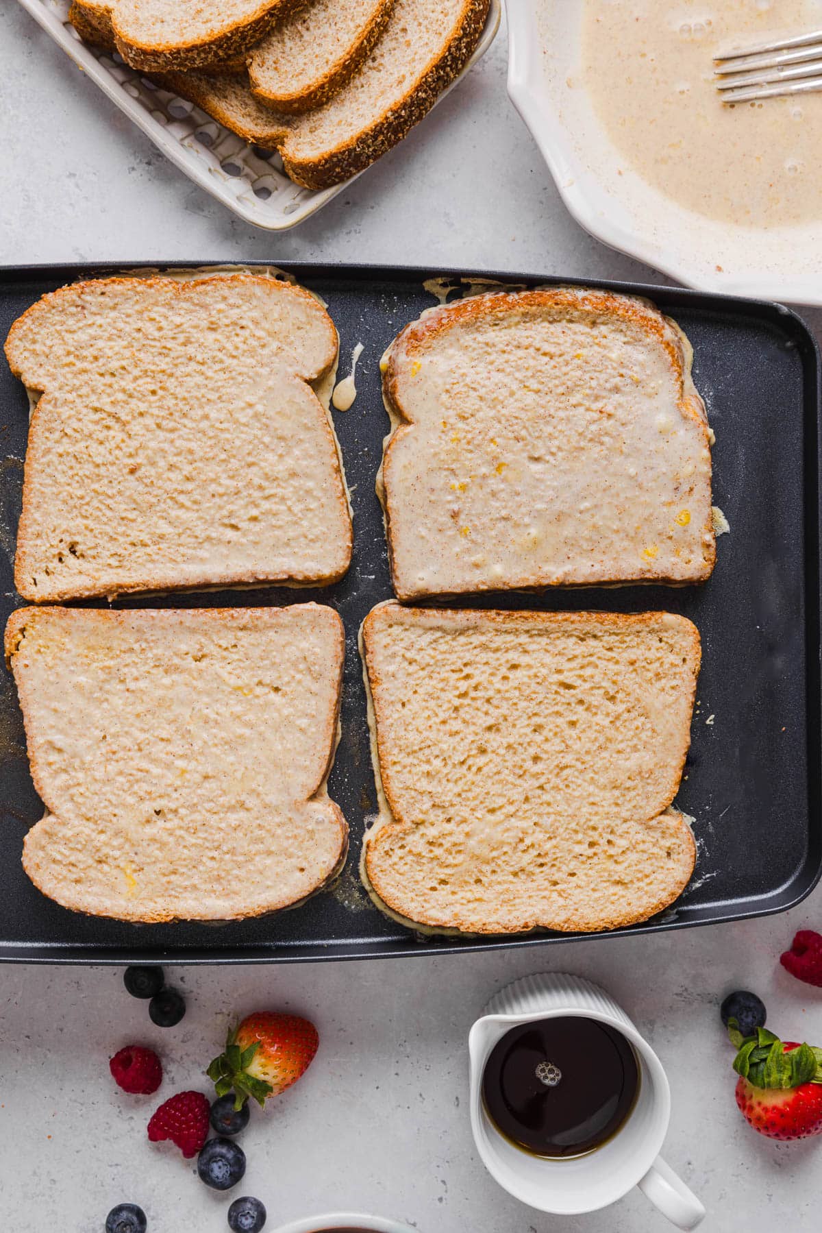 Four pieces of soaked bread on a skillet to cook the french toast.
