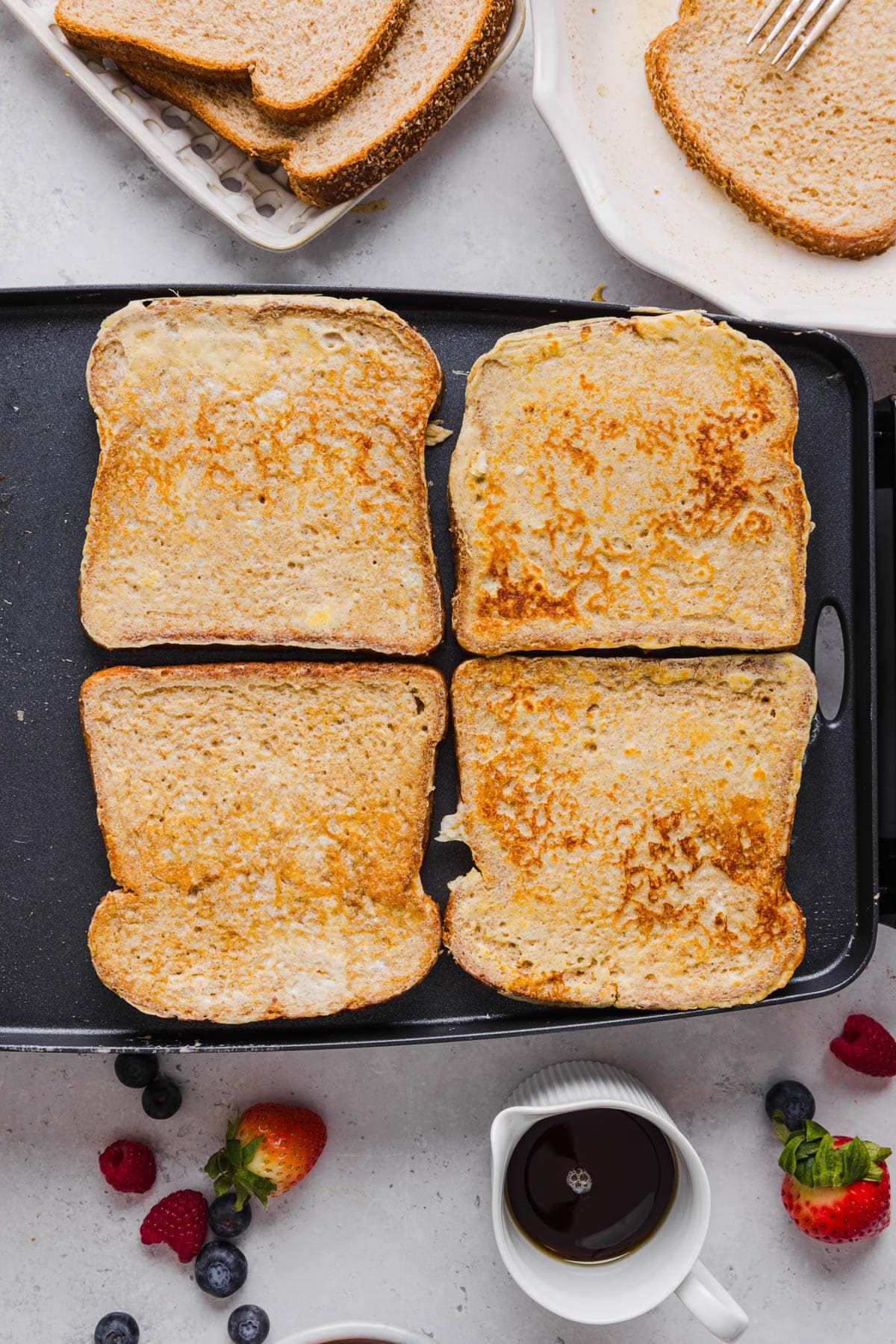 Four pieces of cooked french toast cooked until golden brown on a skillet ready for serving.