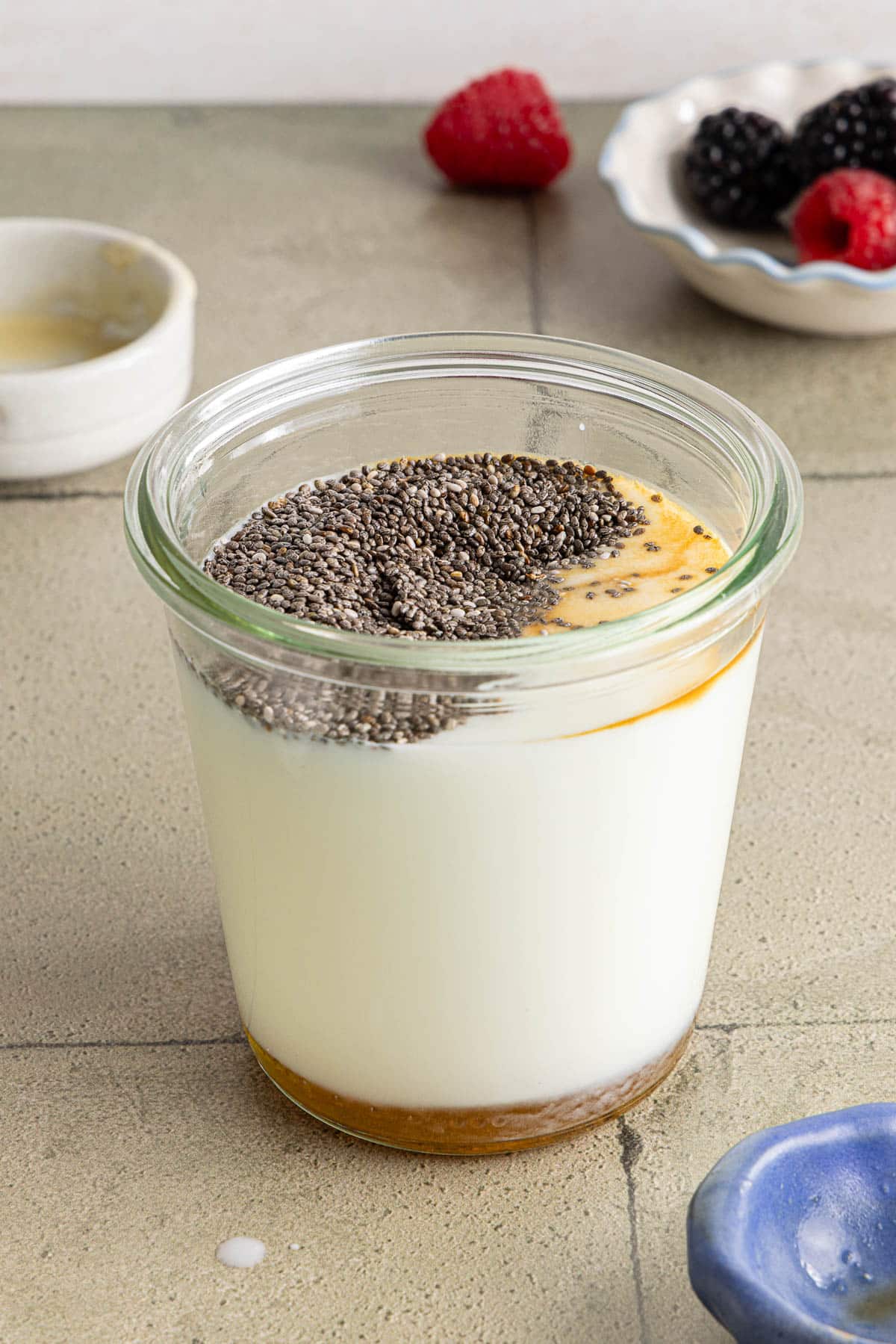 The kefir, honey, chia seeds and vanilla in a small glass container before stirring.