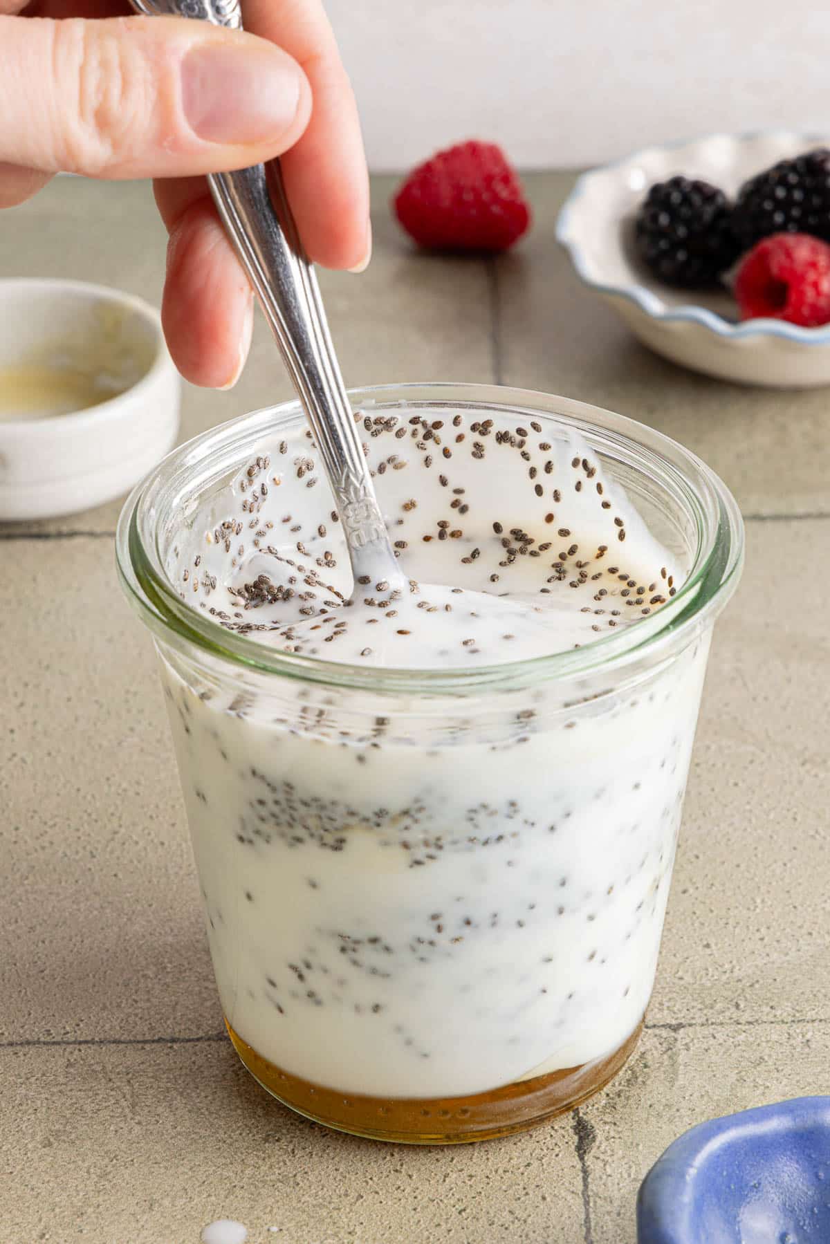 A spoon mixing all of the ingredients together in the glass container.