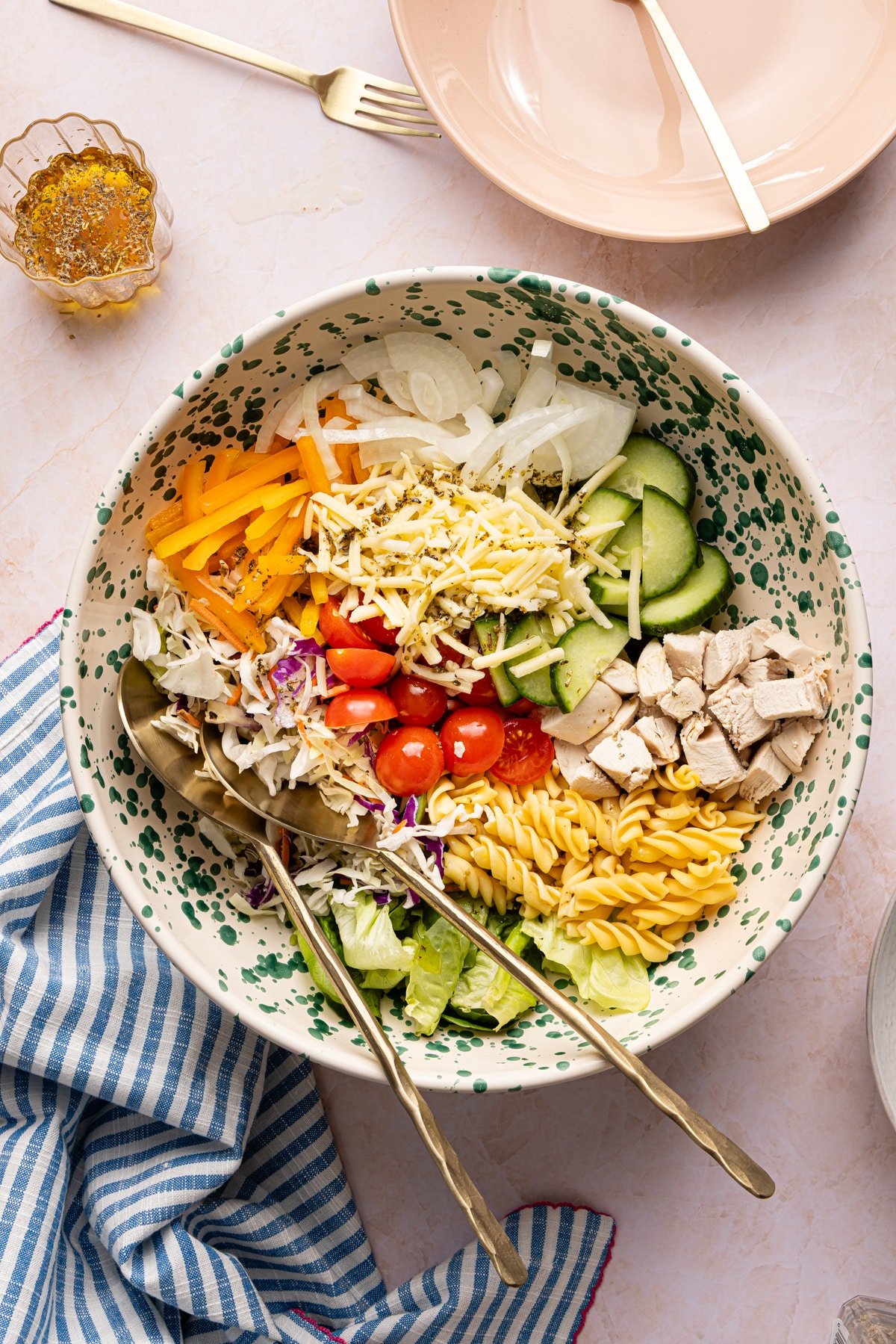 Salad ingredients in a bowl with serving spoons.