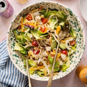 A lunch salad with chicken, pasta, veggies and dressing tossed in a bowl.