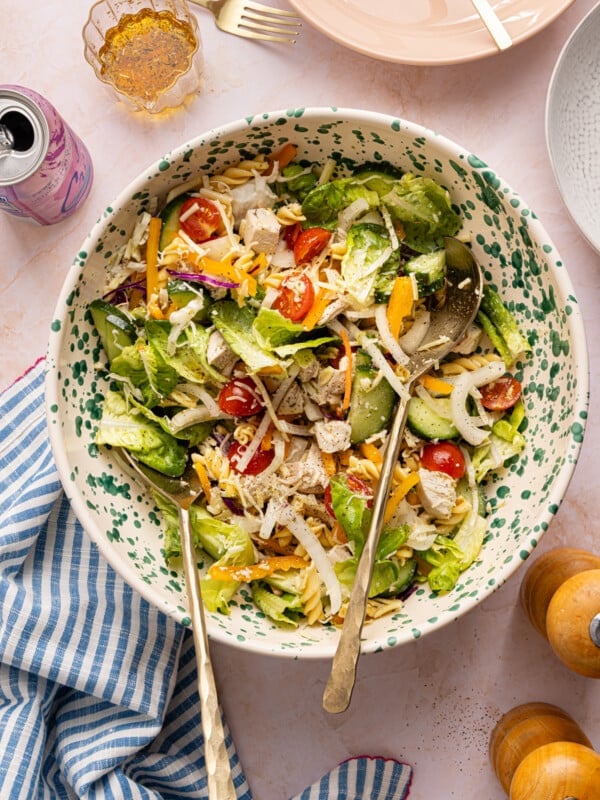 A lunch salad with chicken, pasta, veggies and dressing tossed in a bowl.