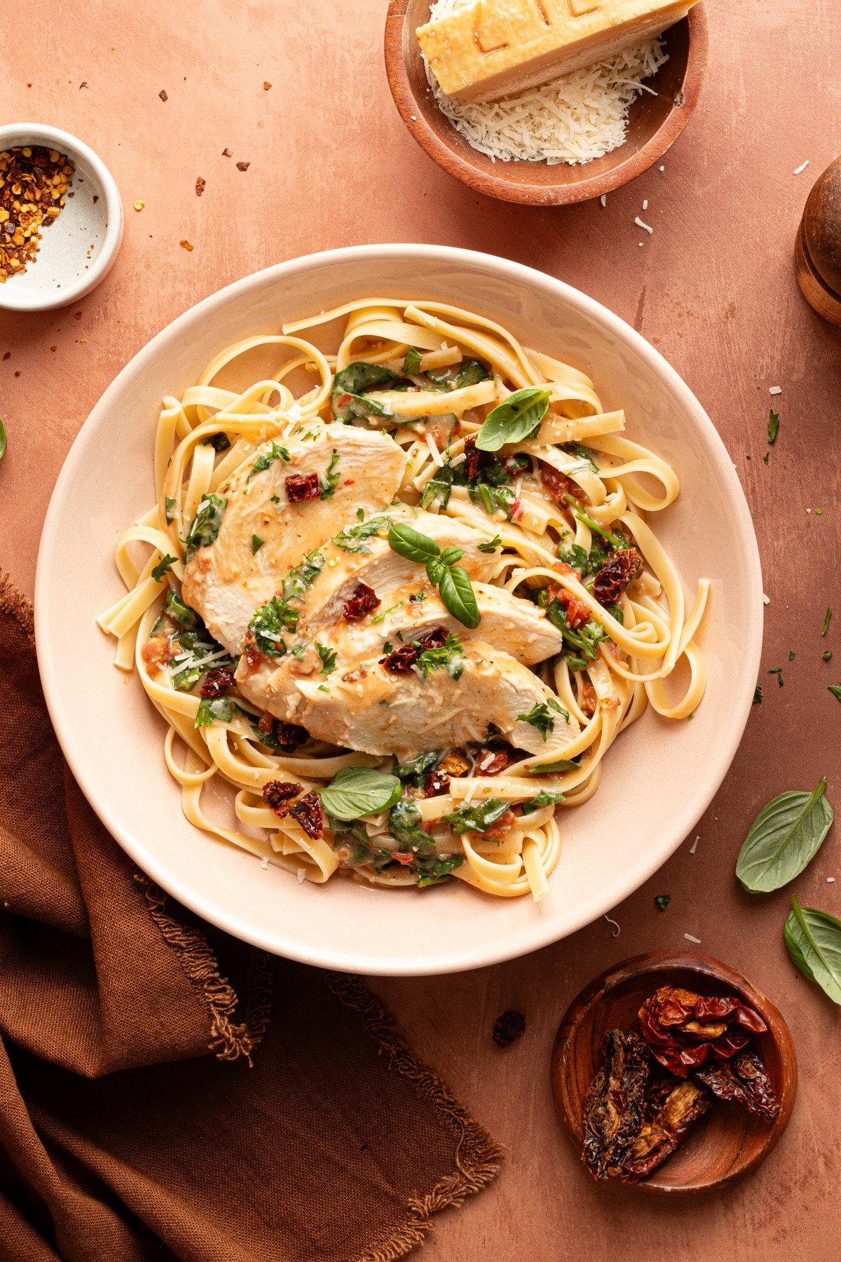 A shallow bowl is filled with a serving of pasta and sliced slow cooker marry me chicken.