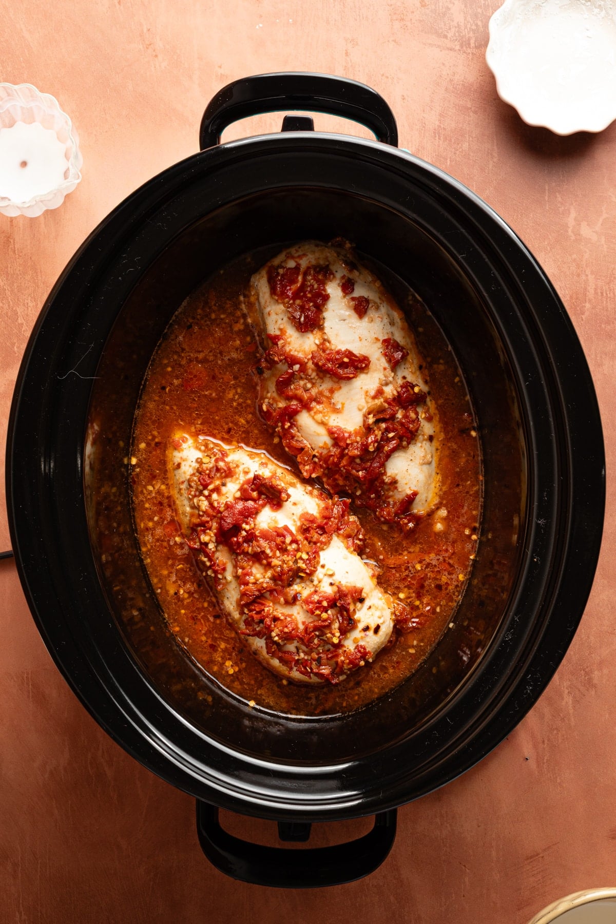 Cooked chicken breasts in the slow cooker after cooking with the tomato broth mixture for 2 hours.
