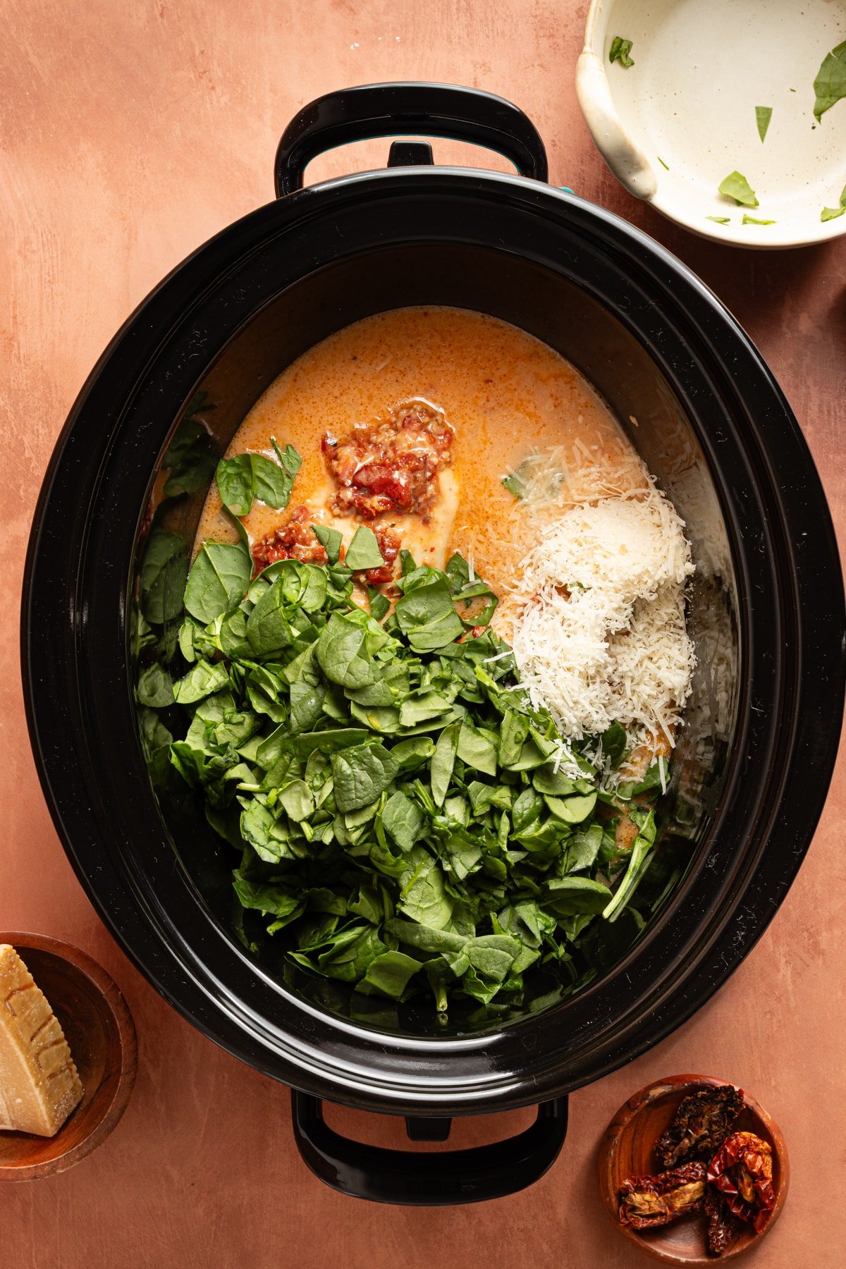 The lemon juice, parmesan cheese, and chopped spinach added to the slow cooker before stirring.