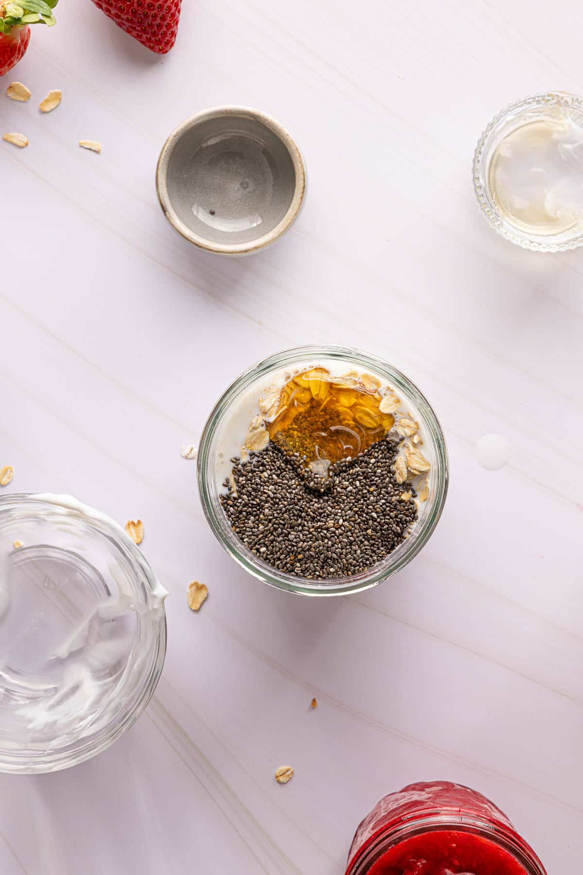 All of the ingredients for pb and j overnight oats in a jar before stirring.