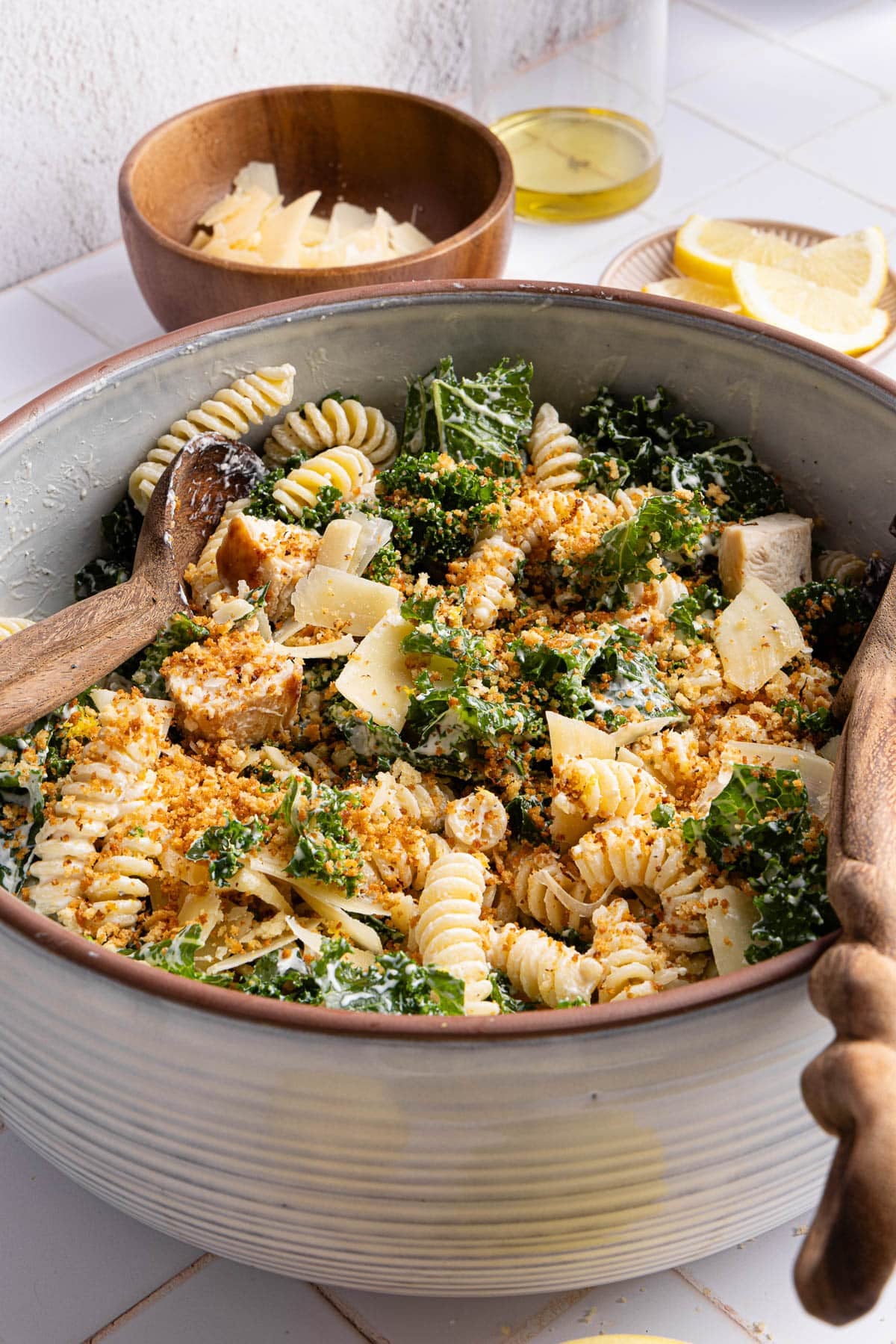 The finished salad with the shaved parmesan and toasted breadcrumbs in a large bowl with the serving utensils.