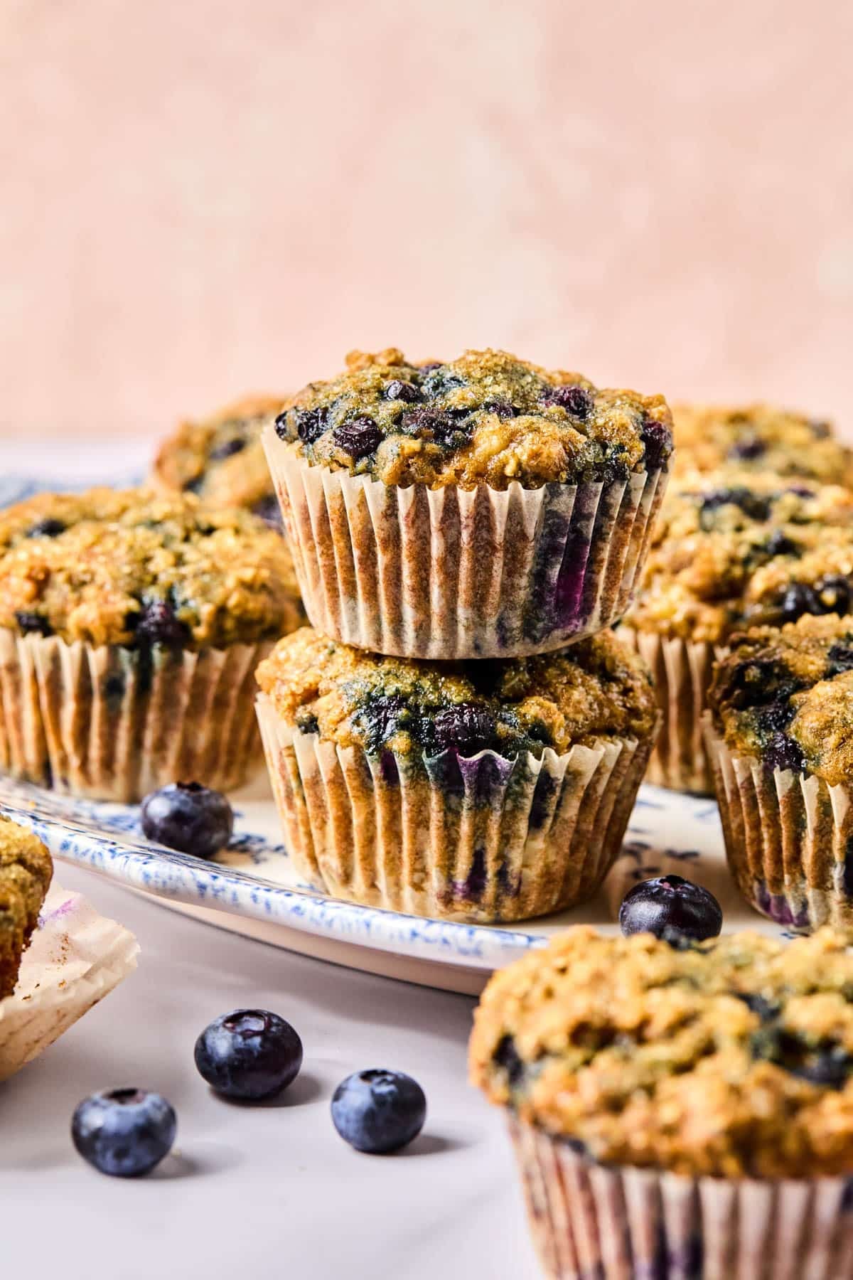 Two banana blueberry oatmeal muffins stacked on top of each other on a white dish on a countertop.