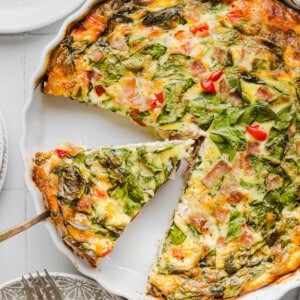 A serving utensil picking up a slice of crustless cottage cheese quiche from the baking dish.