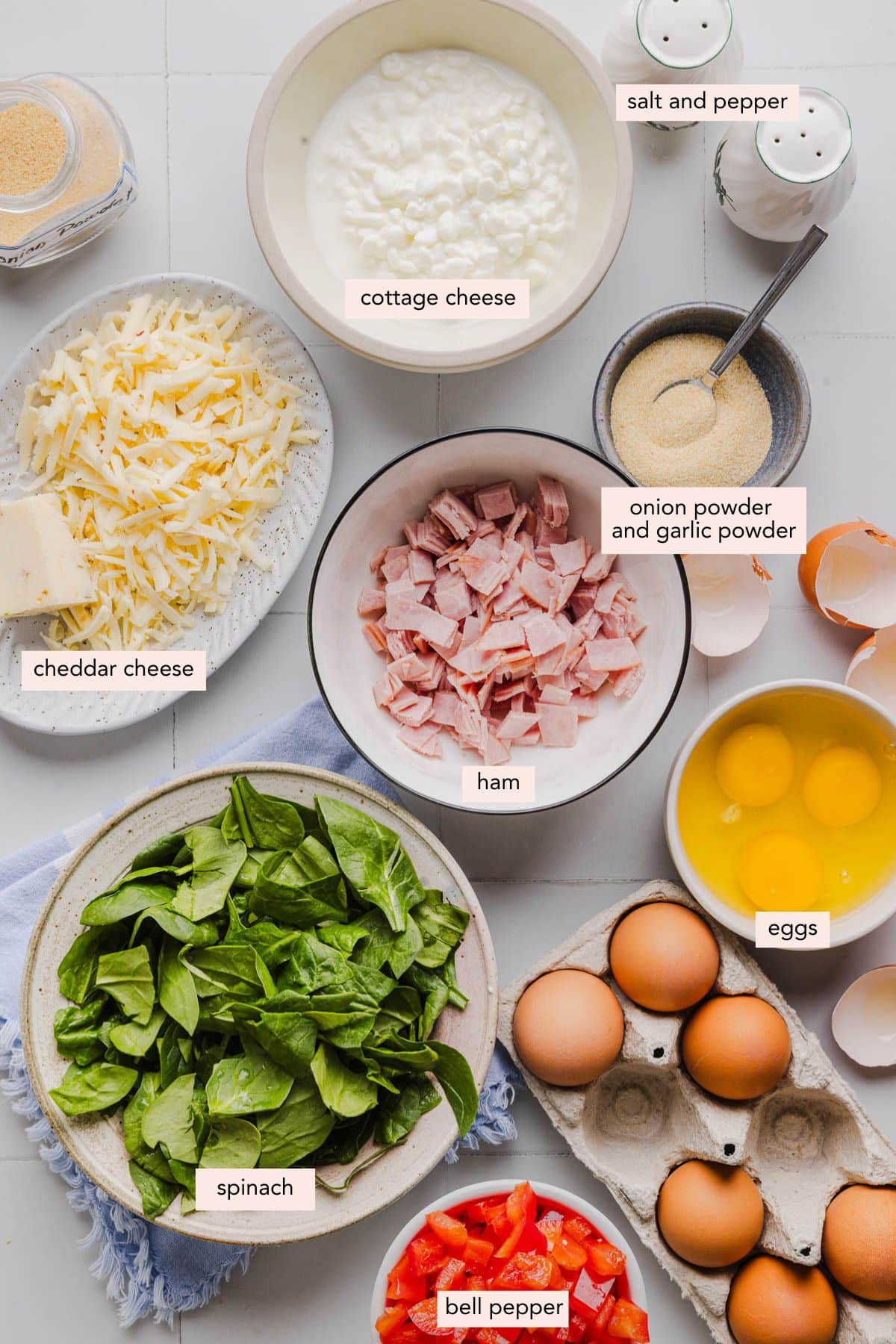 All of the ingredients for crustless cottage cheese quiche in bowls on a white countertop.