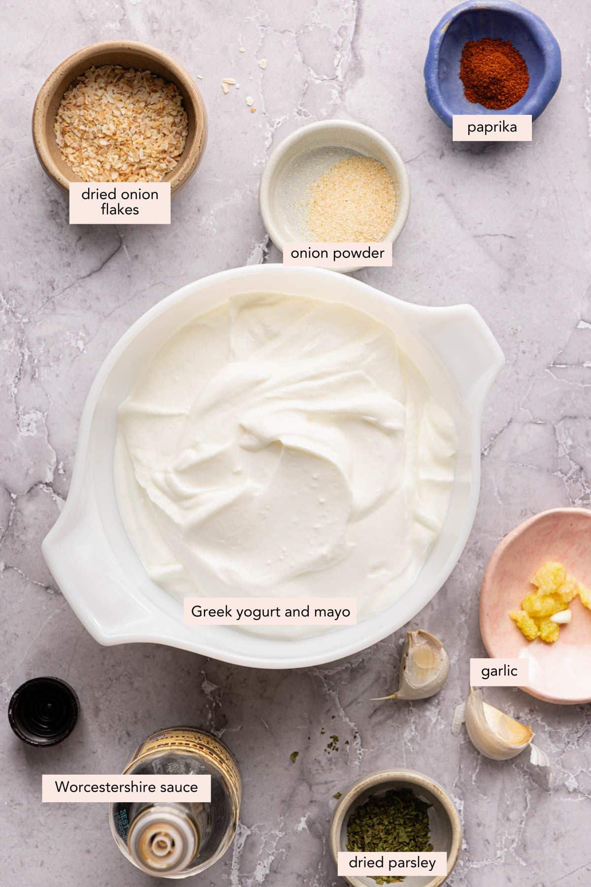 All of the ingredients for greek yogurt french onion dip in bowls on a countertop.