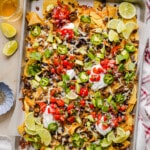 A baking sheet filled with ground turkey nachos loaded with avocado, jalapenos, tomatoes and more.