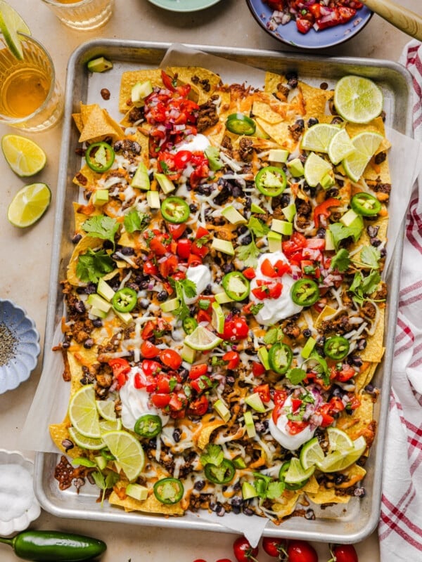 A baking sheet filled with ground turkey nachos loaded with avocado, jalapenos, tomatoes and more.