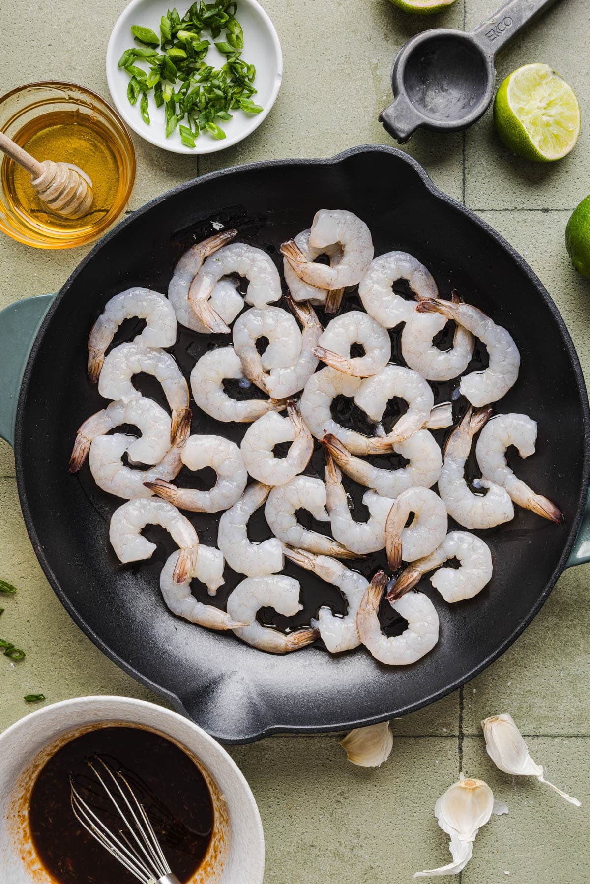The raw shrimp in the skillet with hot oil.
