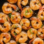 The cooked honey sriracha shrimp in the pan garnished with sliced green onions.