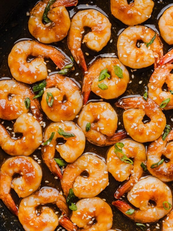 The cooked honey sriracha shrimp in the pan garnished with sliced green onions.