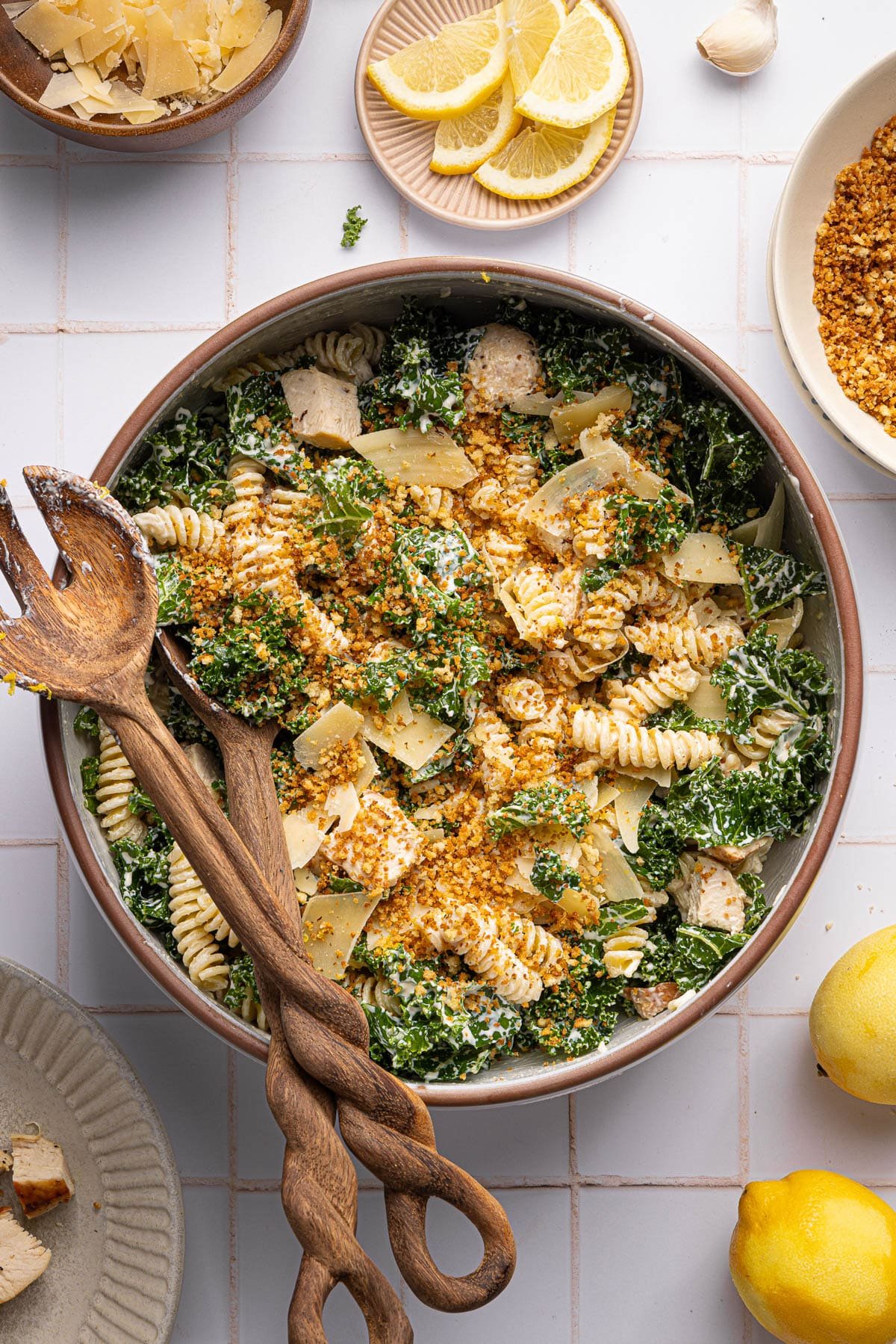 The finished kale caesar pasta salad in a large bowl on a white countertop.