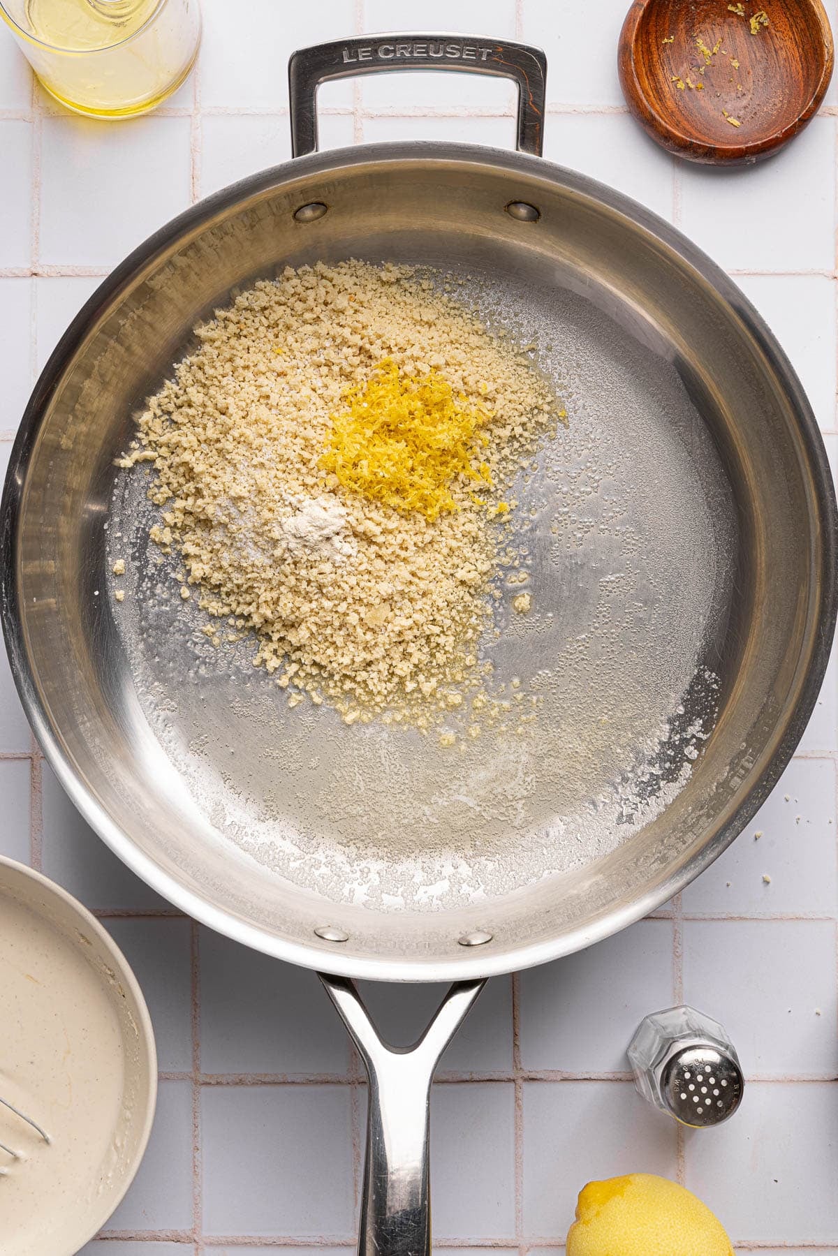 The breadcrumbs in a large skillet with the olive oil, lemon zest, garlic powder, and salt.
