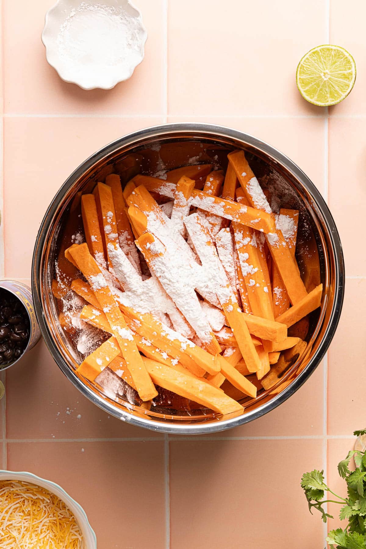 A bowl of the dried sweet potato pieces with cornstarch on top of them.