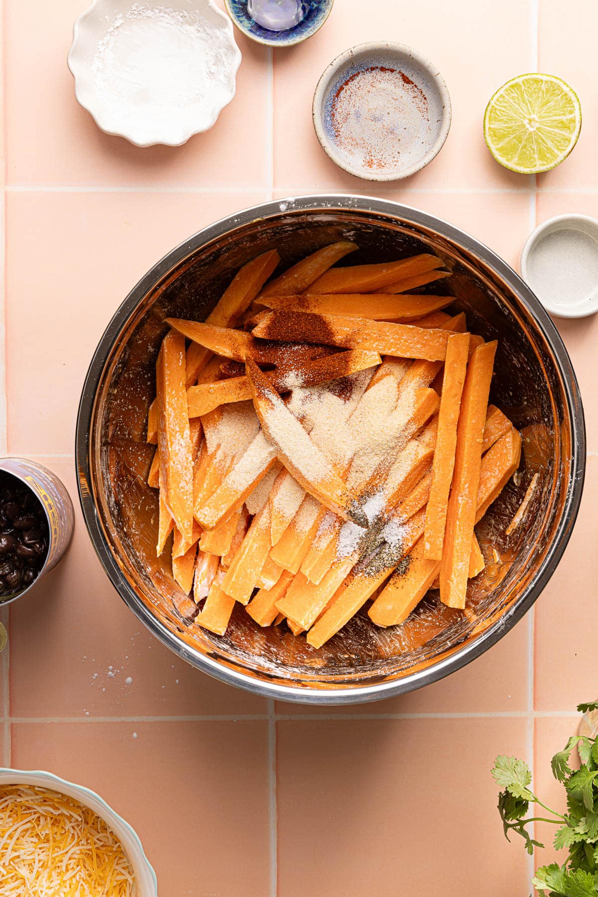 The sweet potatoes in the bowl with the spices and olive oil before tossing.