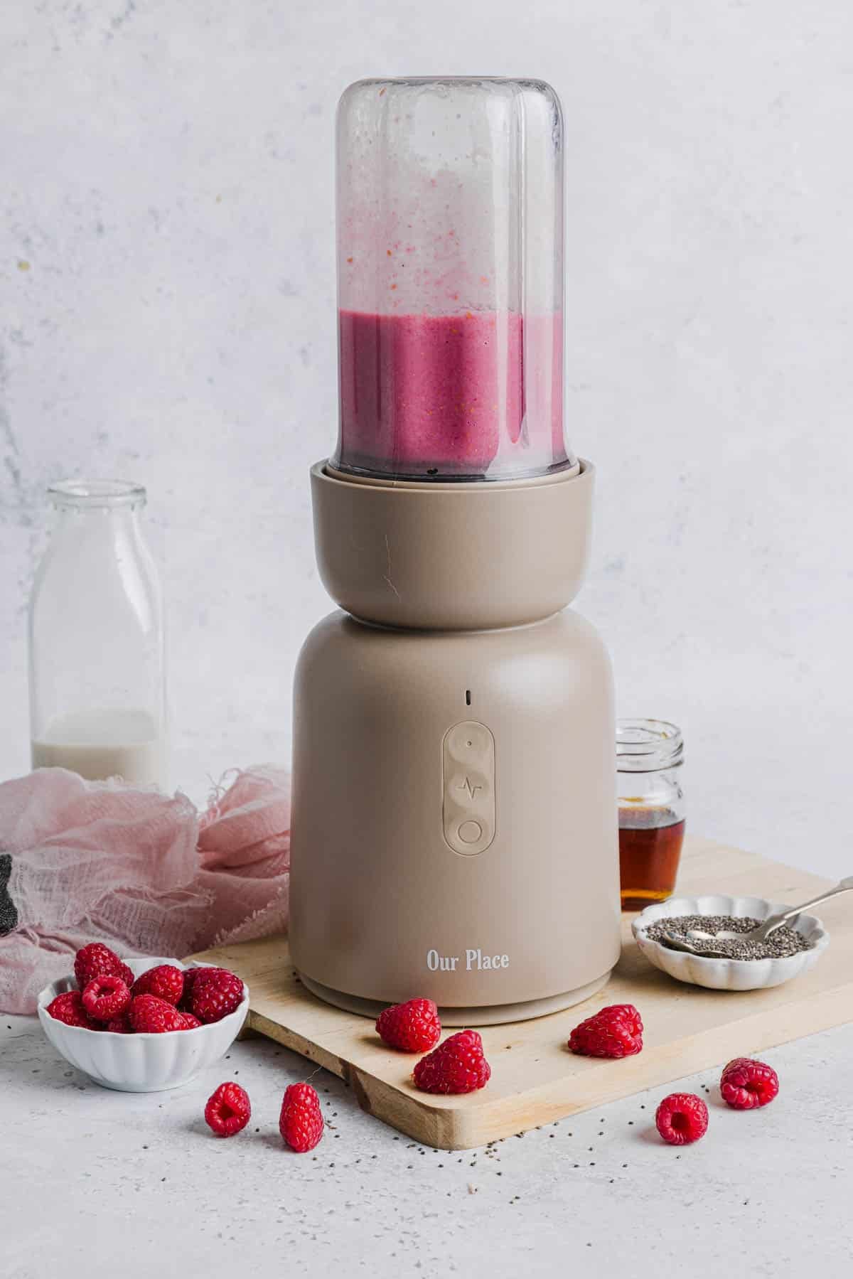 The raspberry milk mixture sits in a blender on a countertop.