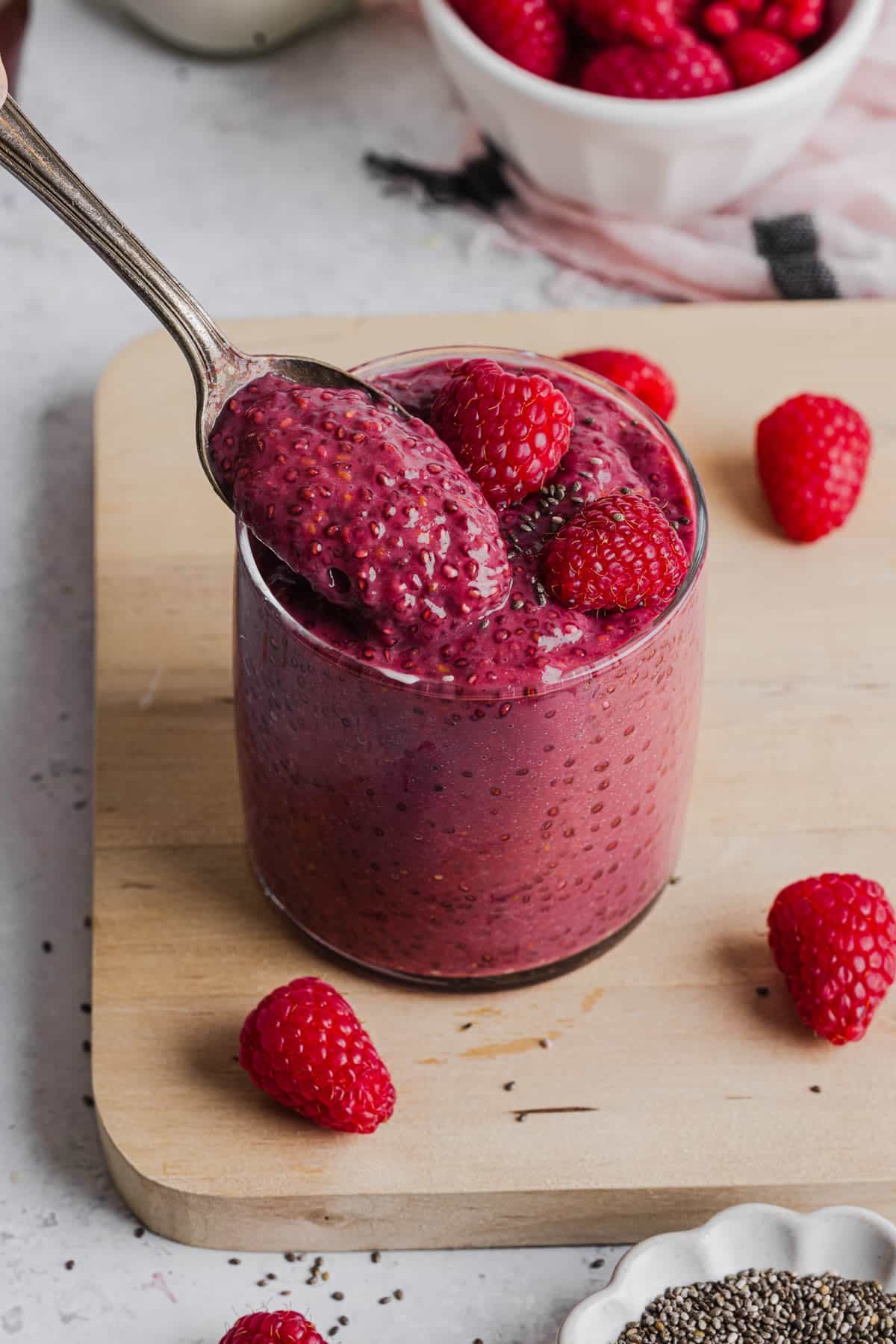 A spoonful of raspberry chia pudding over the jar of the remaining puffing.