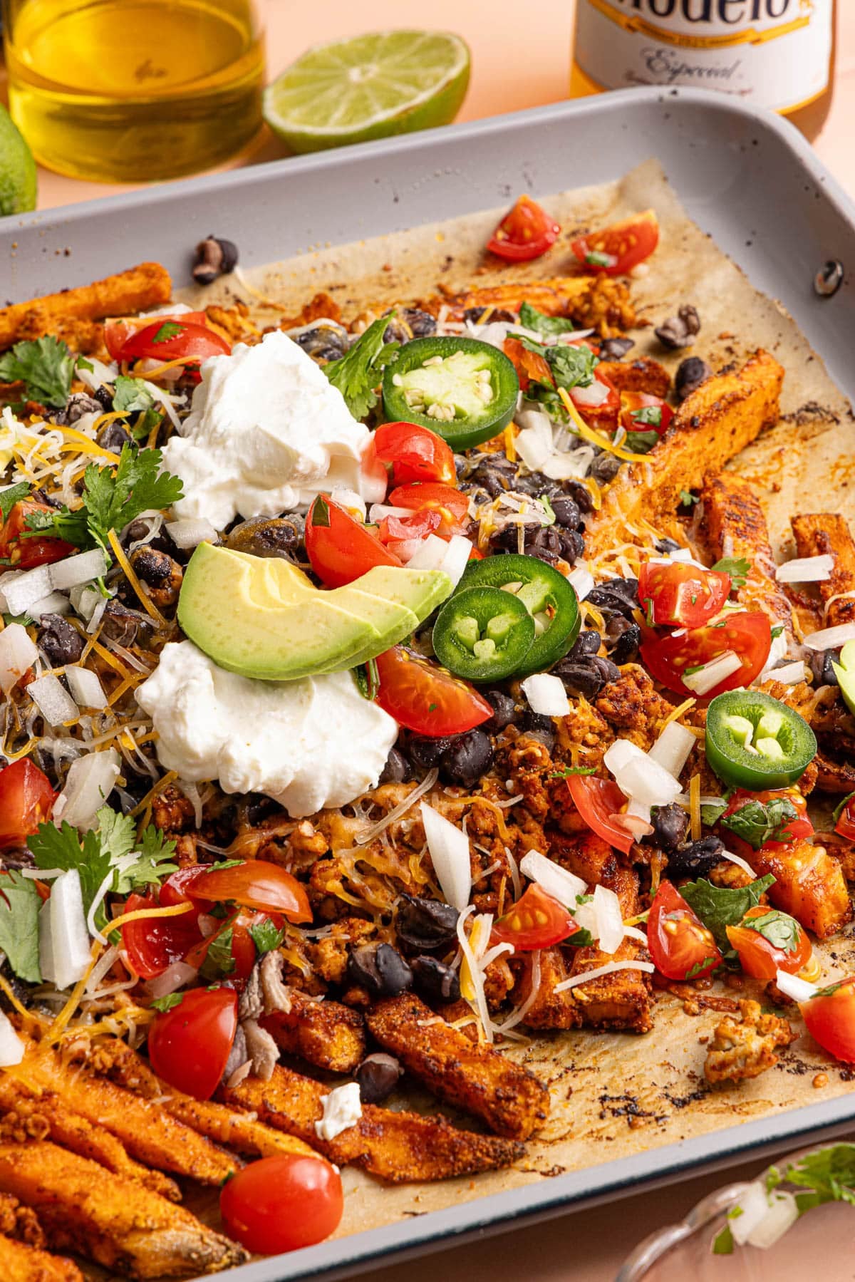 A baking sheet filled with the loaded sweet potato fries sits on a countertop.