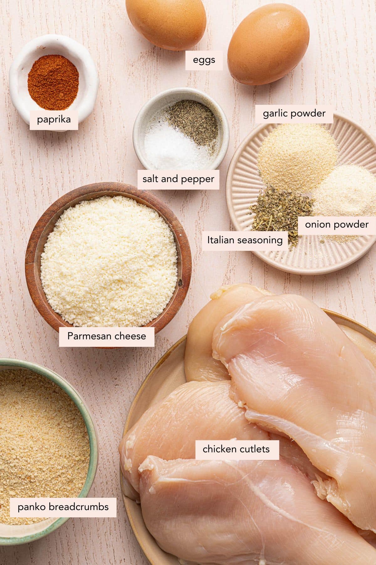 All of the ingredients for baked chicken cutlets in bowls on a countertop.