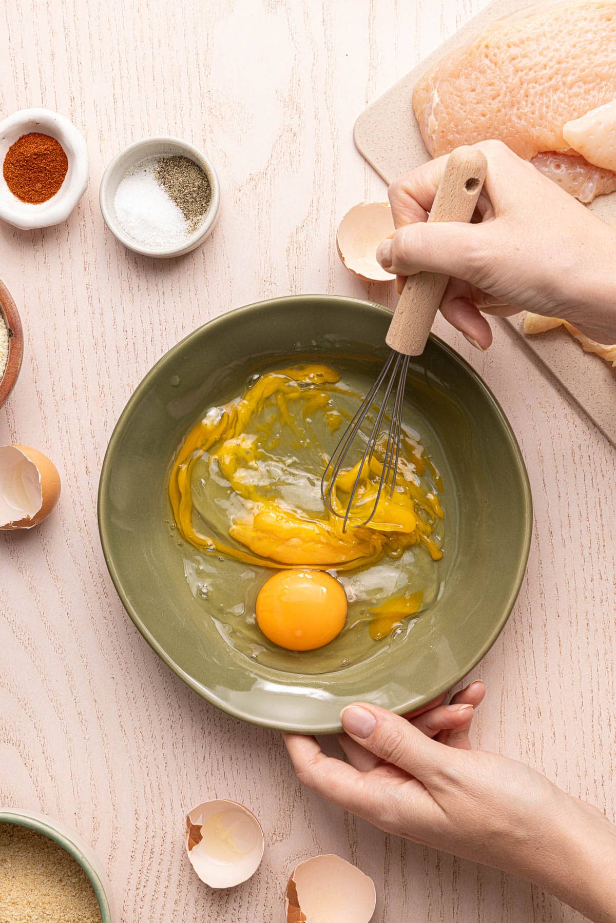 Whisking the eggs in a green bowl on a countertop.