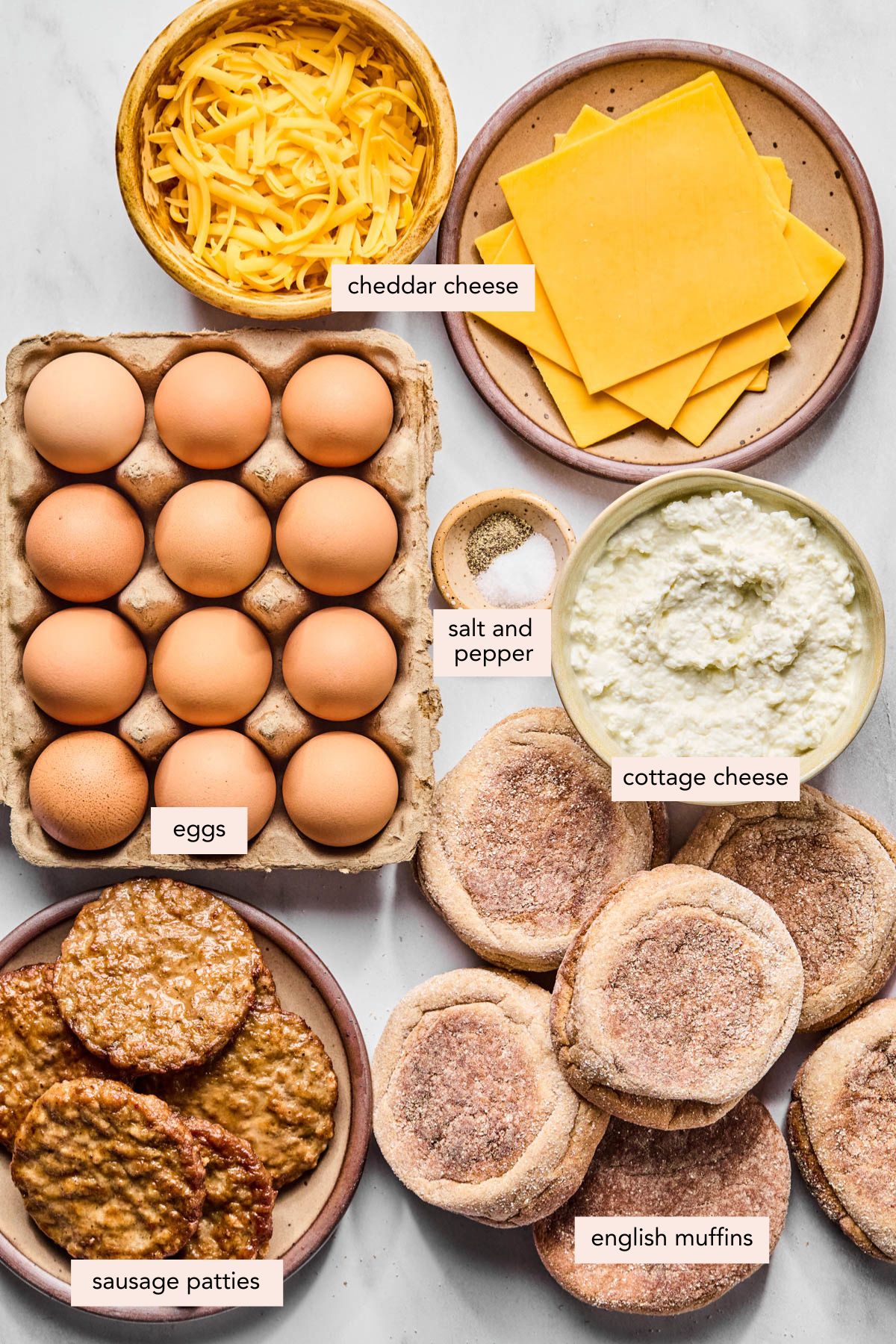 All of the ingredients for breakfast sandwiches in bowls or plates on a countertop.