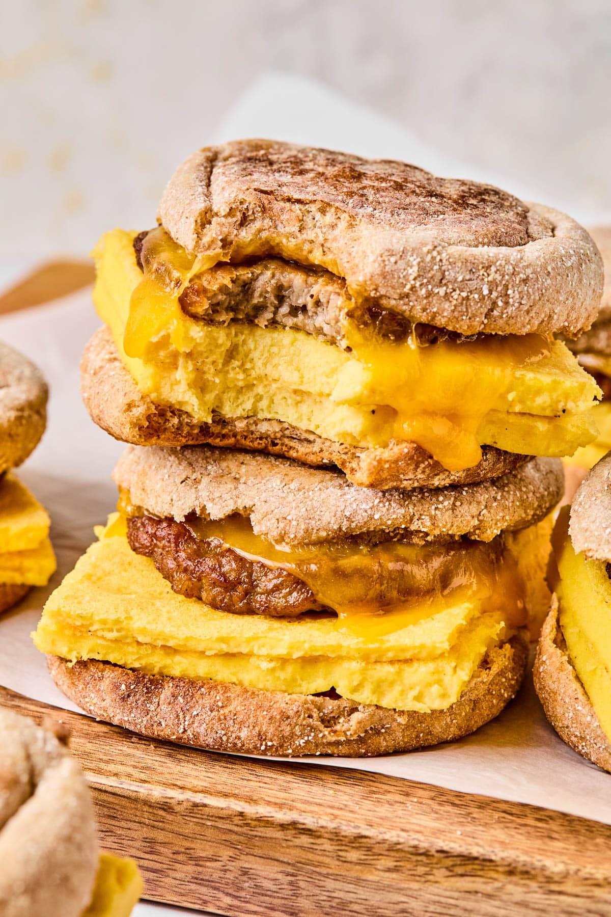 Two breakfast sandwiches stacked on top of each other with the top one having a bite taken out of it.