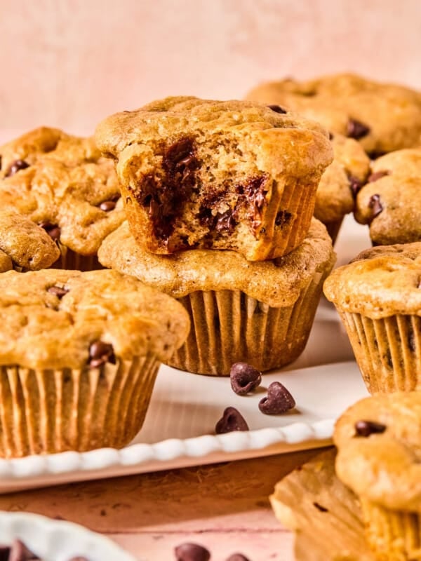 Chocolate chip muffins with cottage cheese stacked on a white serving platter with a bite taken out of the one on top.