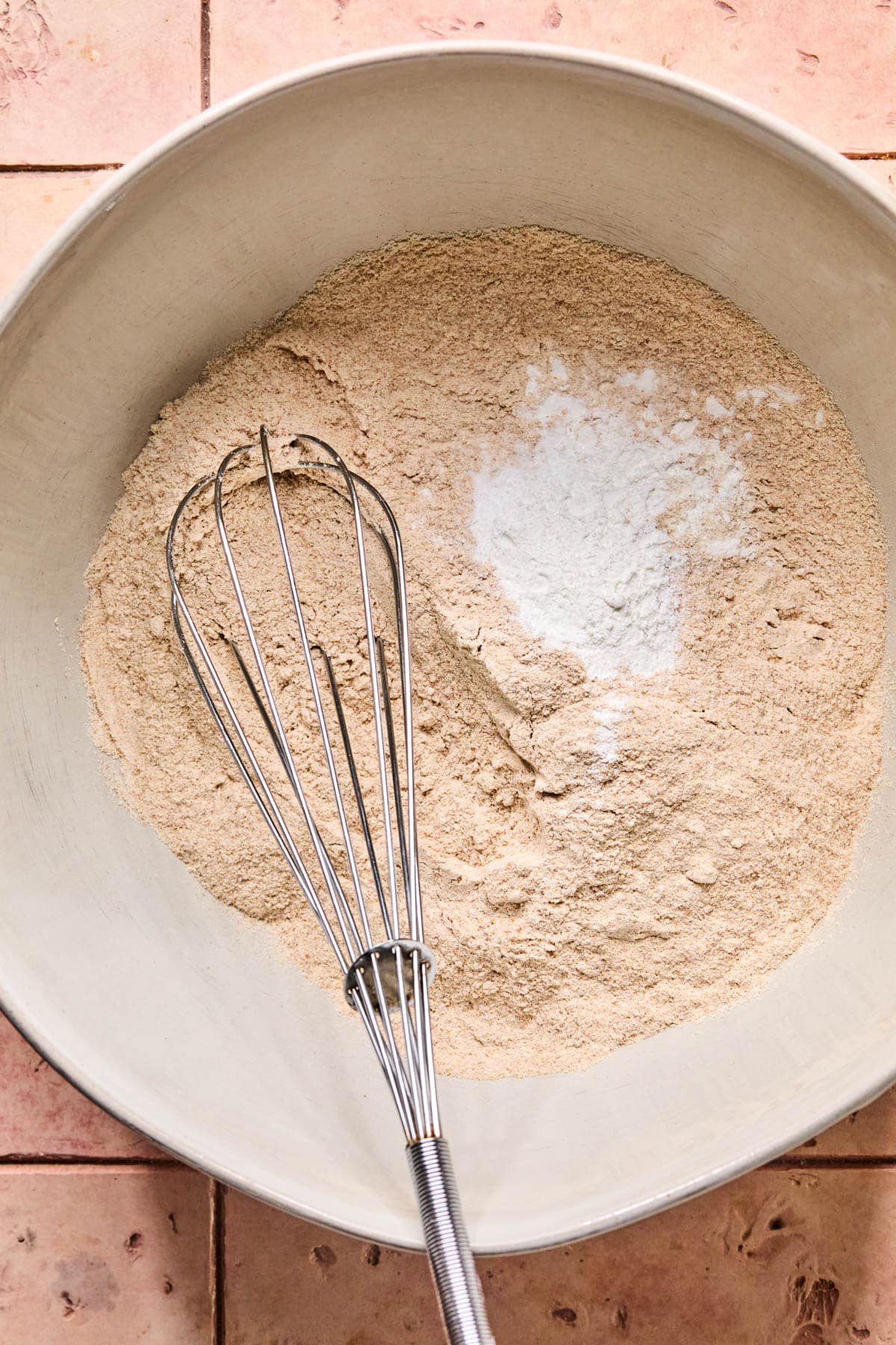 The dry ingredients in a bowl with a whisk before whisking together.