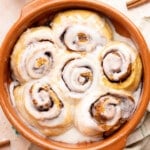 Cottage cheese cinnamon rolls in a baking dish with glaze drizzled on top after baking.
