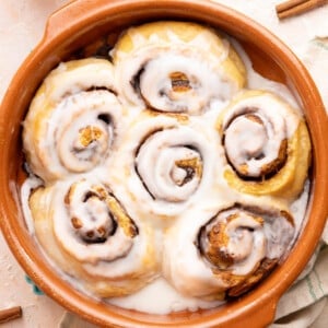 Cottage cheese cinnamon rolls in a baking dish with glaze drizzled on top after baking.