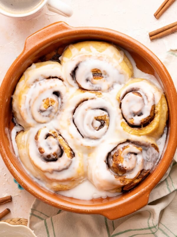 Cottage cheese cinnamon rolls in a baking dish with glaze drizzled on top after baking.