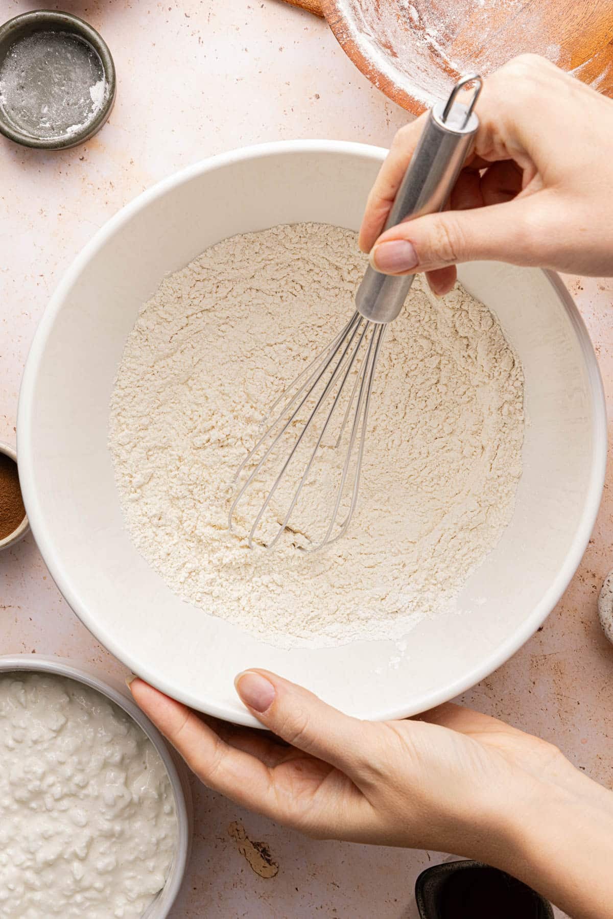 The flour and baking powdered whisked together in a white bowl on a countertop.