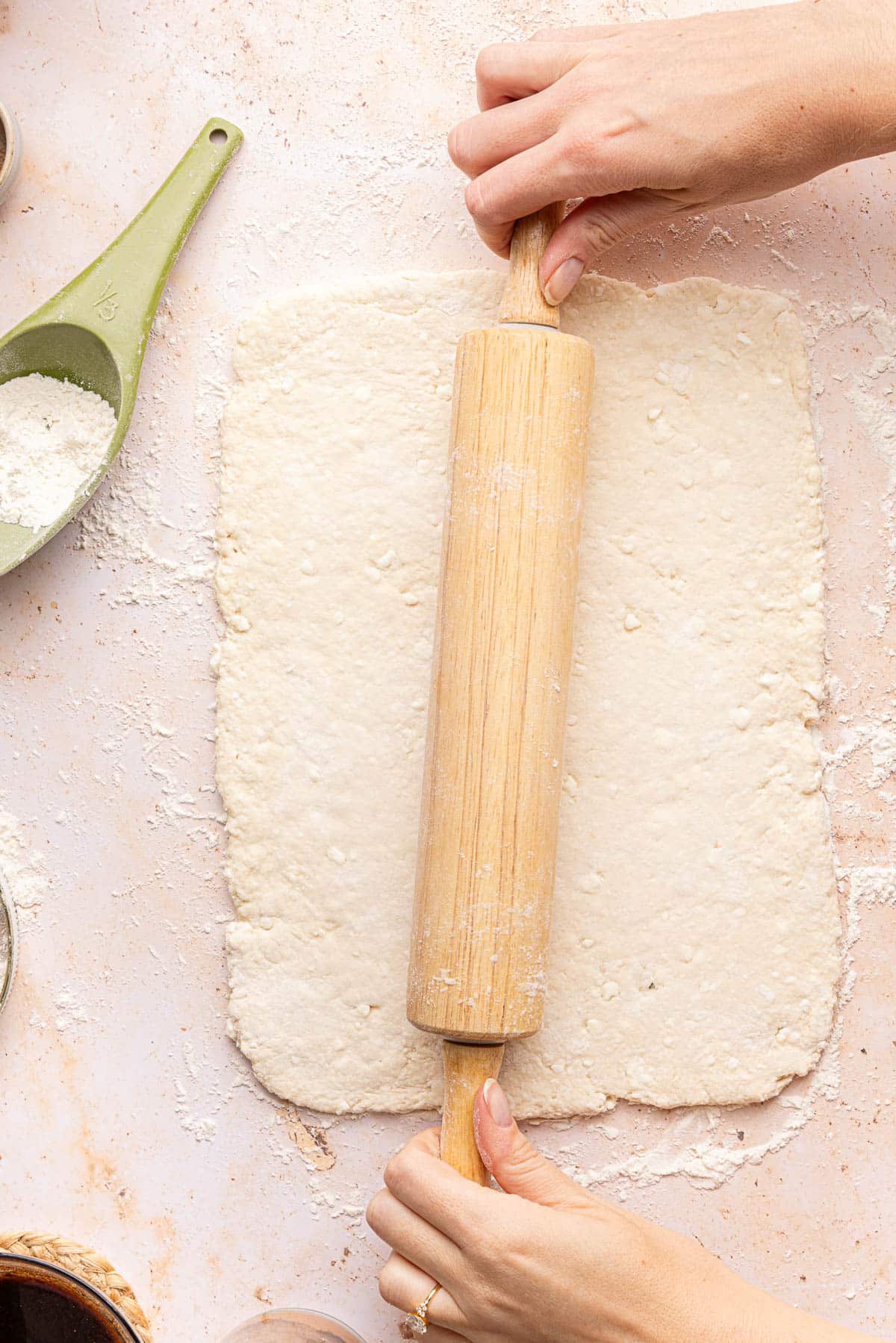 A rolling pin rolling the dough into a rectangle.
