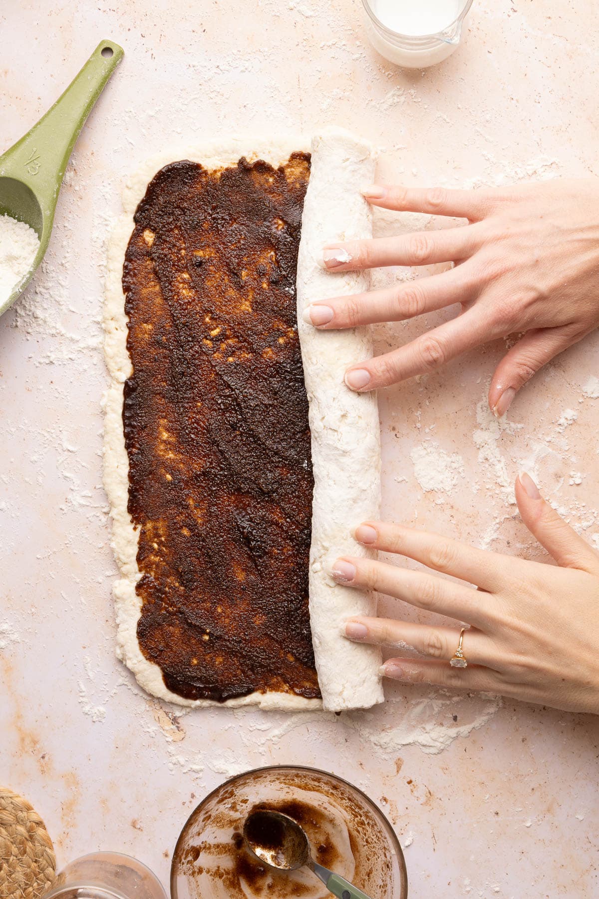 Hands rolling up the dough tightly before slicing into rolls and baking.