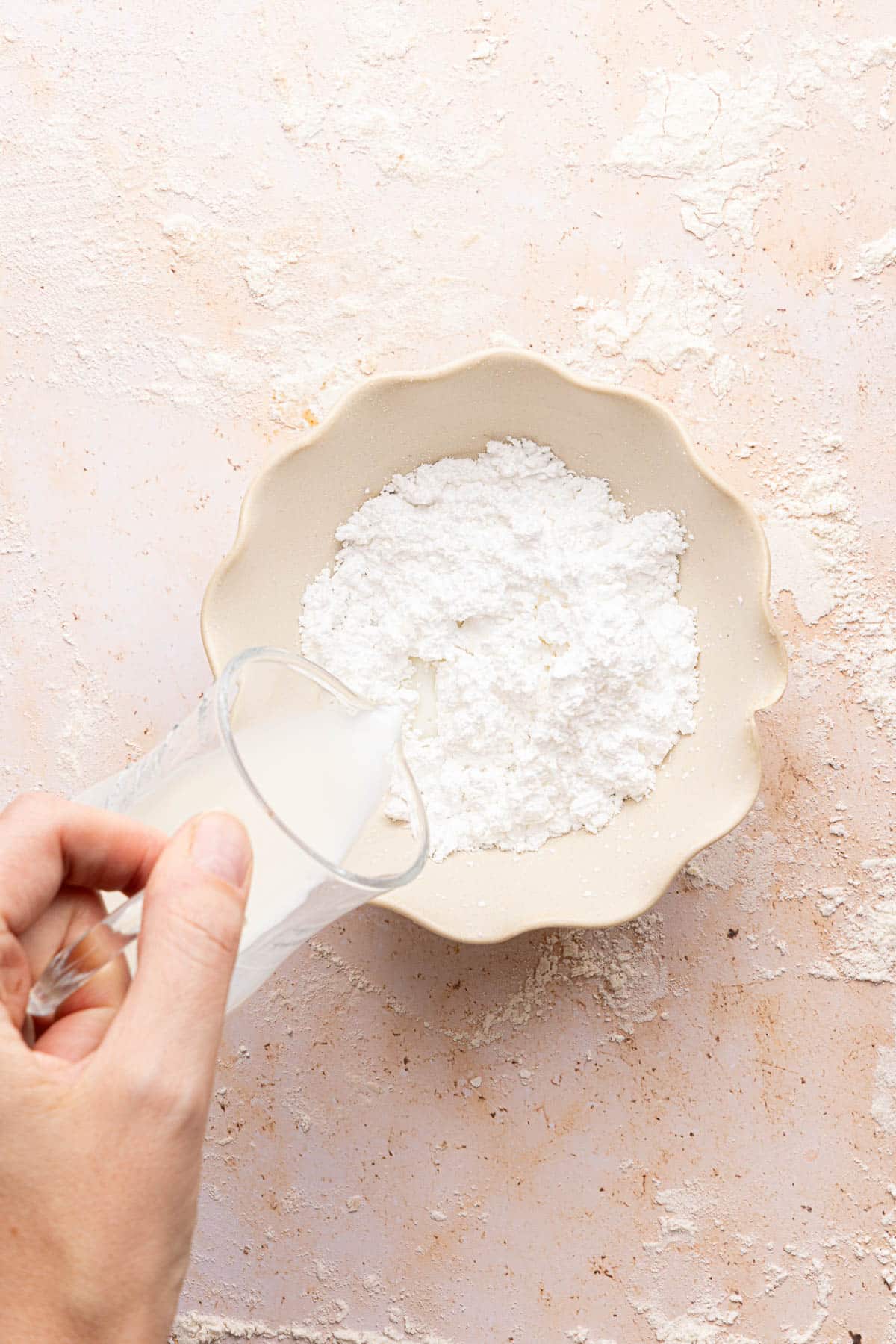 Pouring the milk into the powdered sugar before stirring to make the glaze.