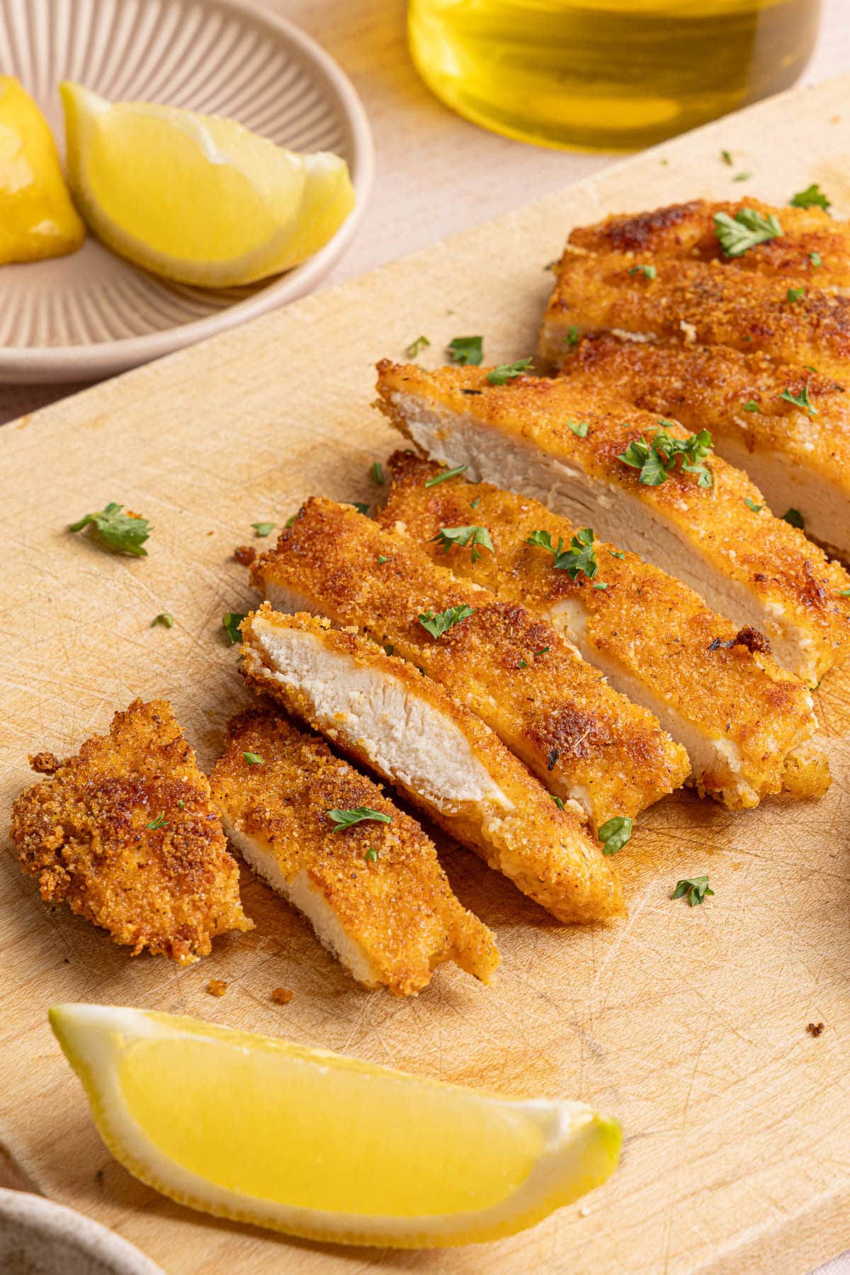 A sliced chicken cutlet on a wooden cutting board.