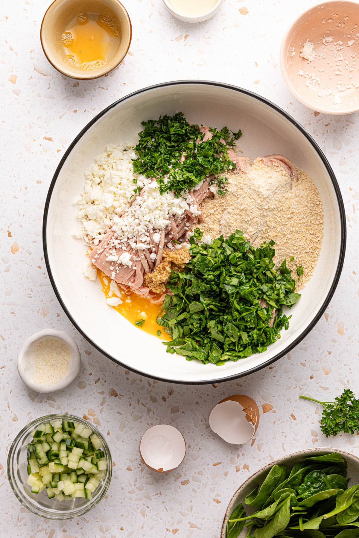 All of the ingredients for turkey feta meatballs (besides the yogurt dill sauce) in a large white bowl on a countertop.