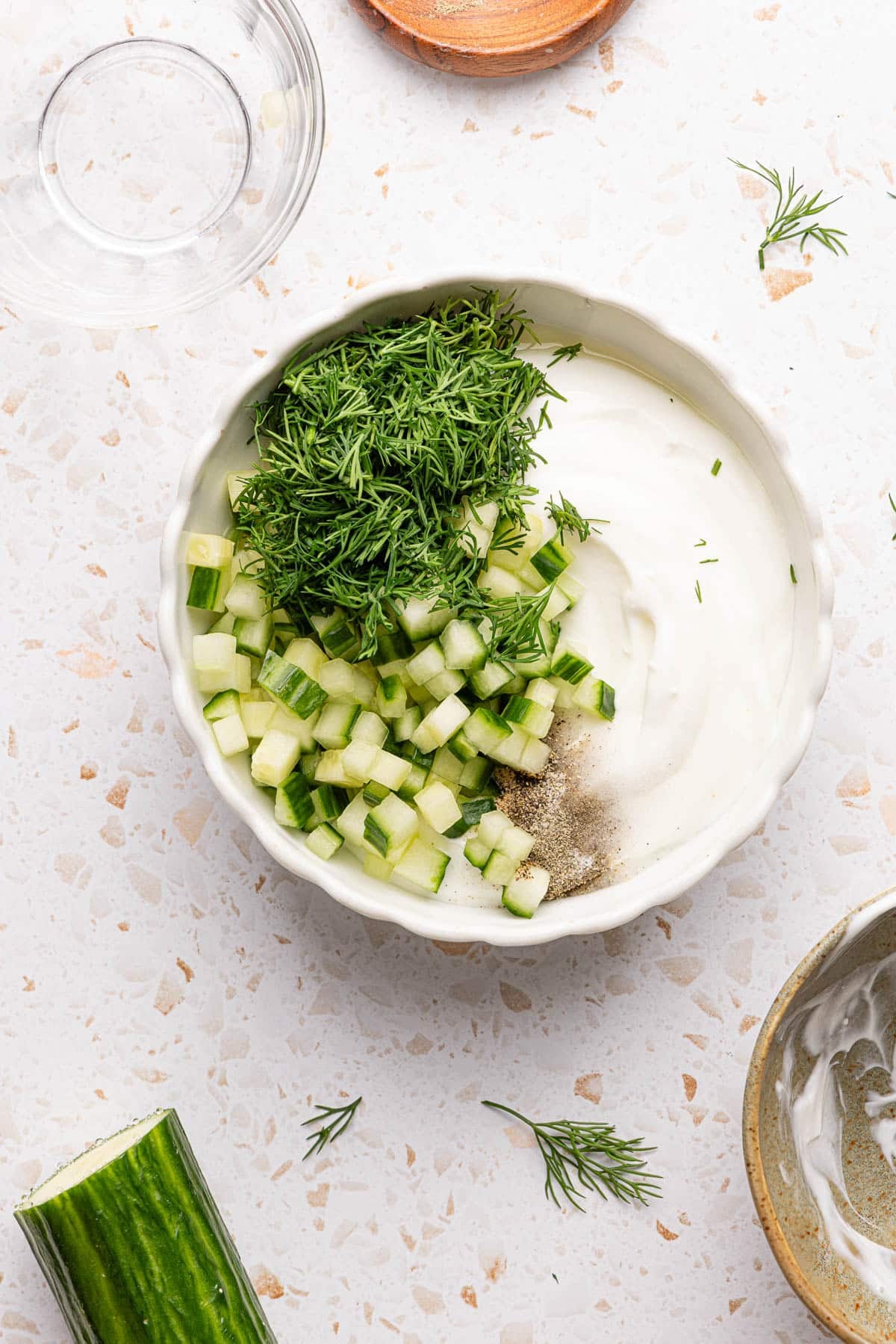 All of the ingredients for the yogurt dill sauce in a white bowl before mixing together.