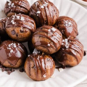 Banana protein balls sitting in a pile on a white plate.