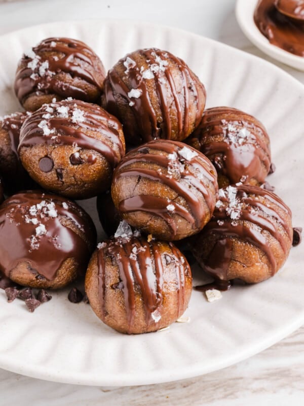 Banana protein balls sitting in a pile on a white plate.