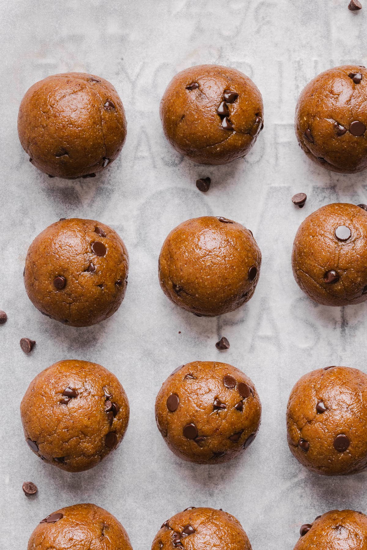 The protein balls on a sheet pan lined with parchment paper before drizzling with the chocolate.
