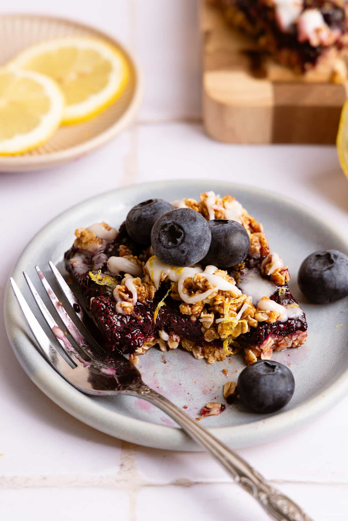 A slice of no bake blueberry lemon bar on a plate with a fork.