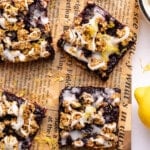 No Bake Lemon Blueberry Bars on parchment paper with some fresh blueberries garnished on the side.