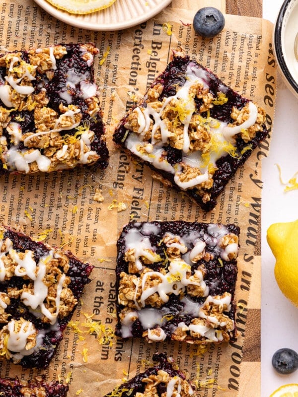 No Bake Lemon Blueberry Bars on parchment paper with some fresh blueberries garnished on the side.